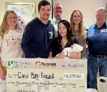 A group of people, including Carus Kincaid and her parents, holding a large check for $1,529 from Path2College 529 Plan and Piedmont Columbus Regional hospital